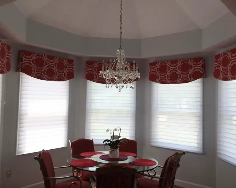 Custom red circle-pattern valances over Silhouette shades in bay window dining room by Ash Street Upholstery in Springfield, IL