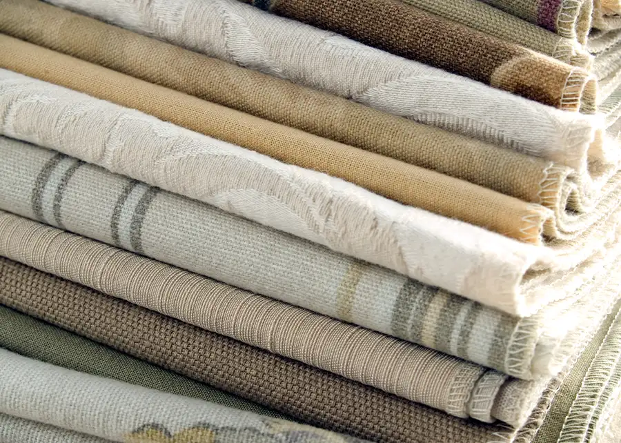 Stack of upholstery and drapery fabric swatches available at Ash Street Upholstery, serving Springfield IL interior design projects with AFAR Imports & Interiors