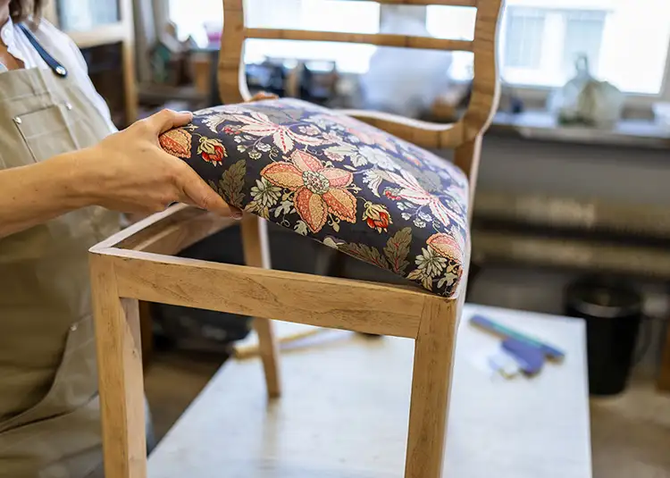 Ash Street Upholstery craftsman hand-upholstering a wood-frame chair with floral fabric, Springfield IL custom upholstery services for AFAR Imports & Interiors